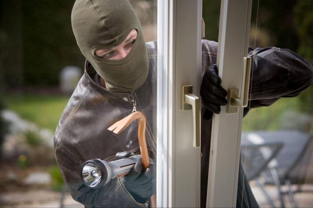 A masked burglar brandishing a gun, poised in a threatening stance.